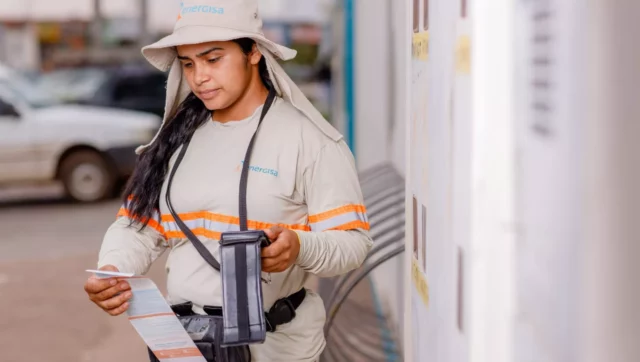 uma Auxiliar Comercial (Leiturista) da energisa fazendo a medição de um contador de energia